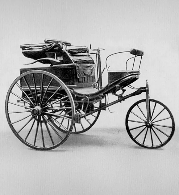     Voiture à moteur Benz Patent - photo historique de la voiture à moteur Benz Patent avec trois roues, un cadre filigrane et une grande banquette, le moteur est monté derrière le siège.
